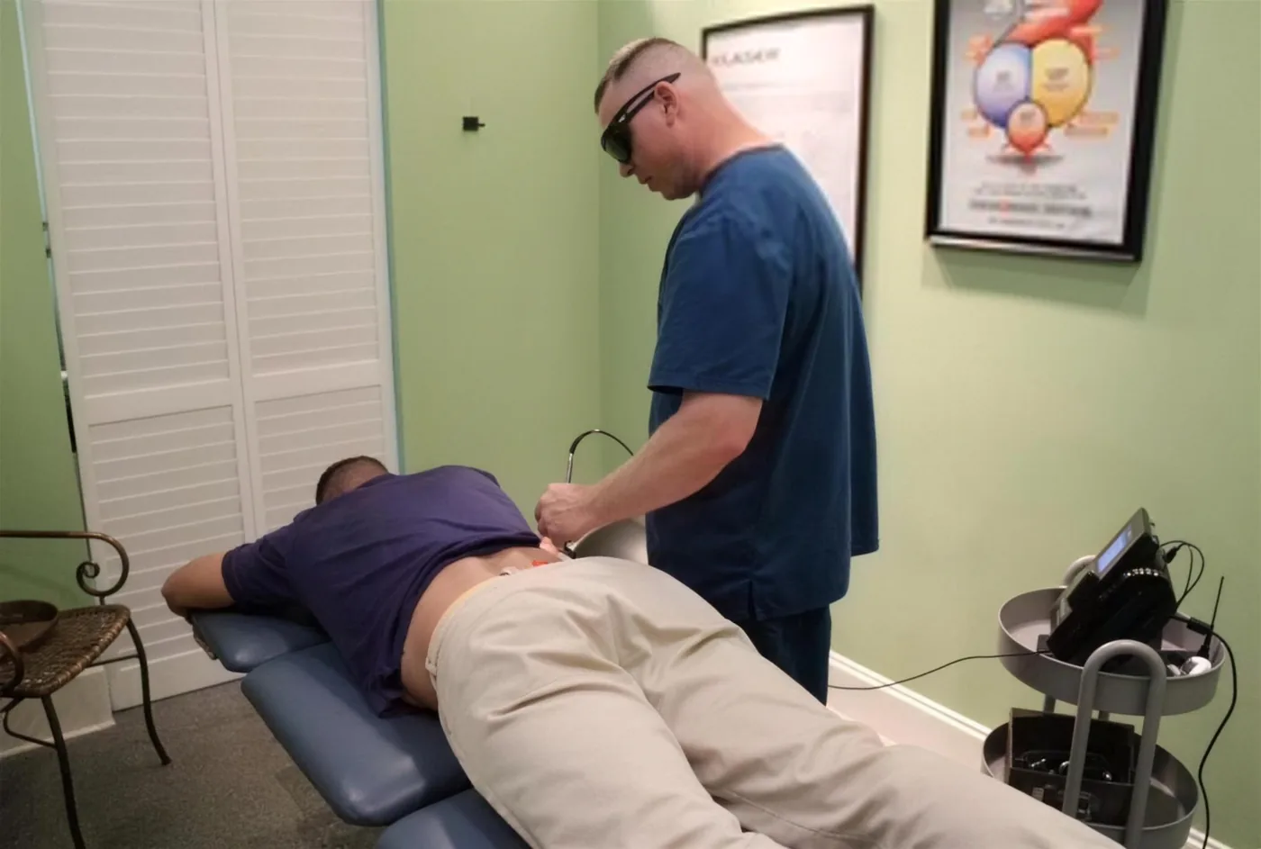 Laser therapy being applied to a patient’s lower back at Strand Spine Institute