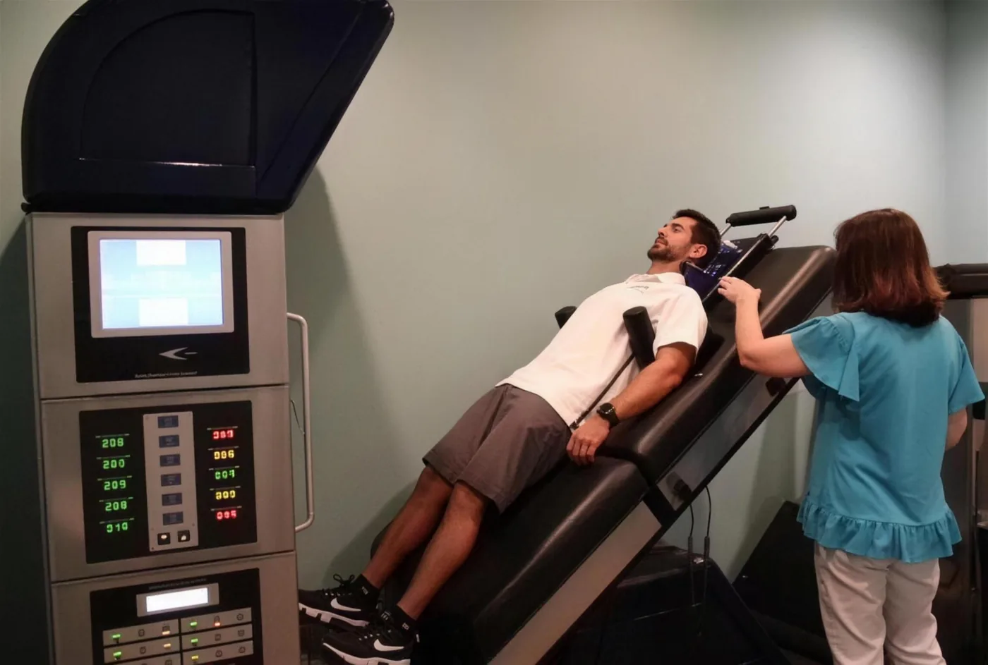 A patient on the spinal decompression table at Strand Spine Institute while a team member sets the unit